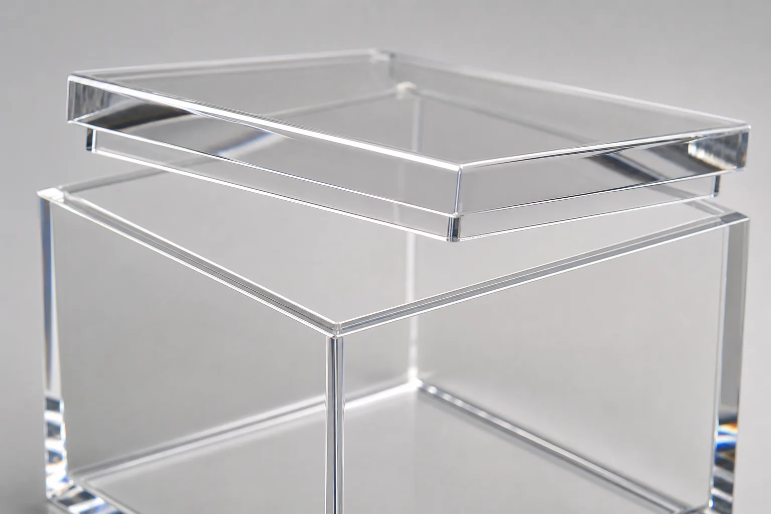 Close-up of a clear acrylic box with lid, lift-off PMMA lid raised at an angle above the box showing the polished lip and the wall edges it seats over