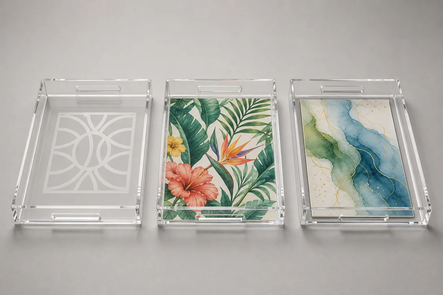 Three clear acrylic trays side by side comparing acrylic tray logo options — a laser-etched frosted mark, a full-color bottom-printed logo, and a replaceable printed insert under the tray floor
