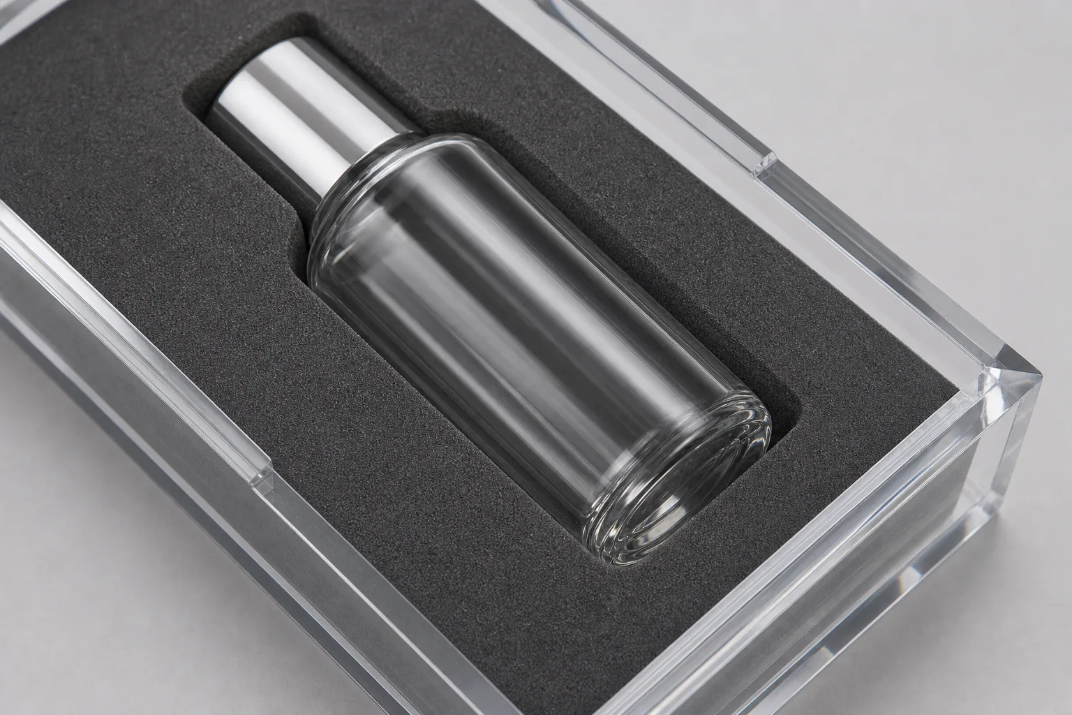 Macro view of a die-cut charcoal EVA foam tray insert compartment inside a clear acrylic tray, a glass cosmetic bottle seated in the recess with even clearance at each wall