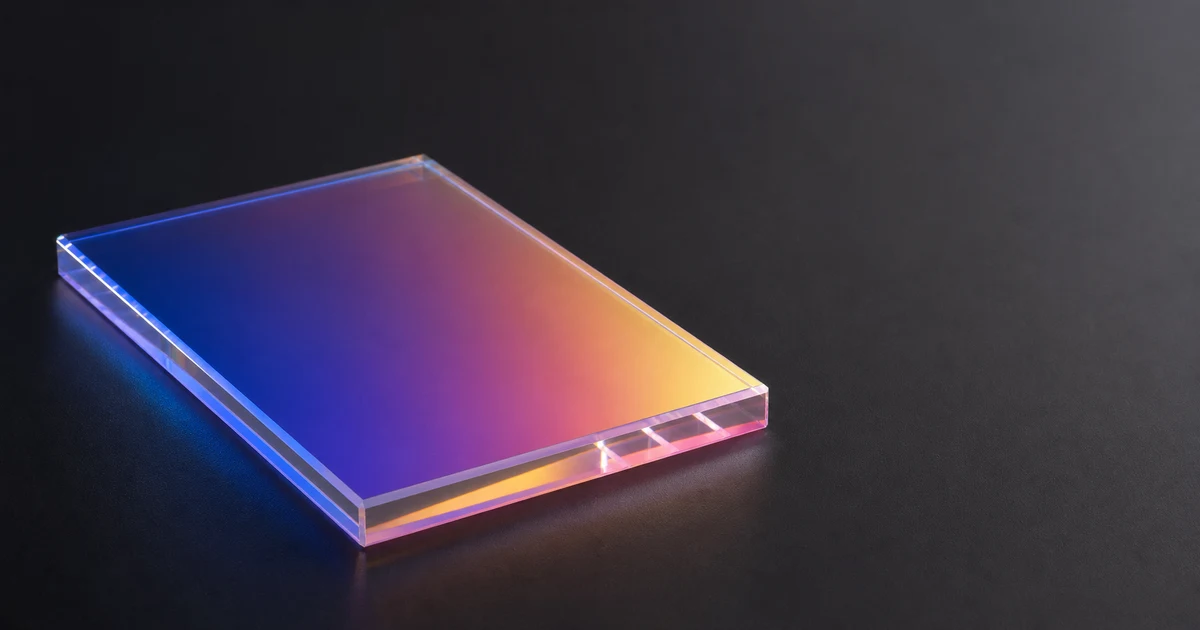 Iridescent acrylic panel angled to catch directional light, generating visible color-shift reflection on neutral background