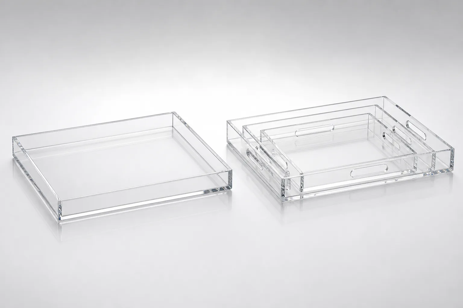 Handleless acrylic serving tray beside a nested set of graduated acrylic serving trays