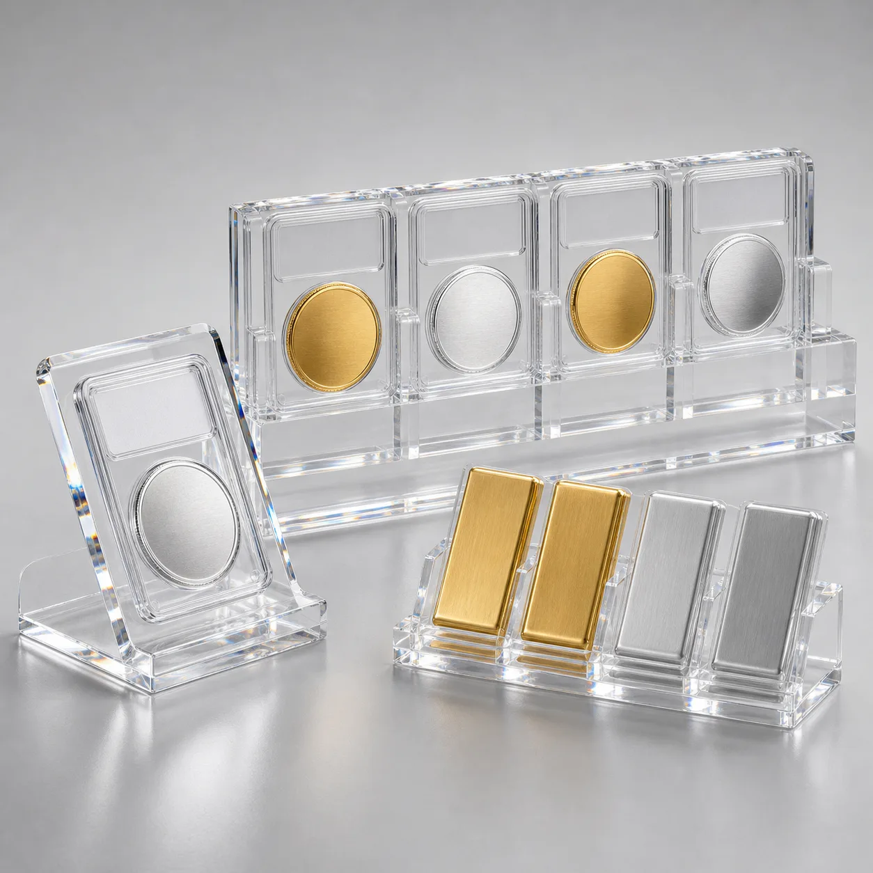 Studio lineup of clear acrylic coin display cases — a single-slab easel stand, a four-slab row display, and a tiered countertop rack holding gold and silver bullion bars